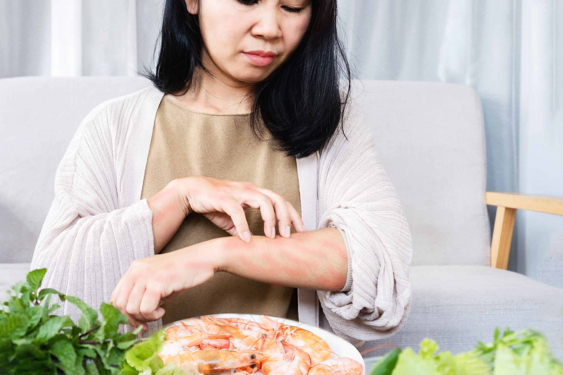 Asian women itching rashes skin and scratching arms caused by food allergies after eating shrimp